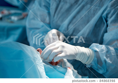 Close up of the face of a patient who is undergoing blepharoplasty. The surgeon cuts the eyelid and performs manipulations using medical instruments Close up of the face of a patient who is undergoing blepharoplasty. The surgeon cuts the eyelid and performs manipulations using medical instruments 84868398