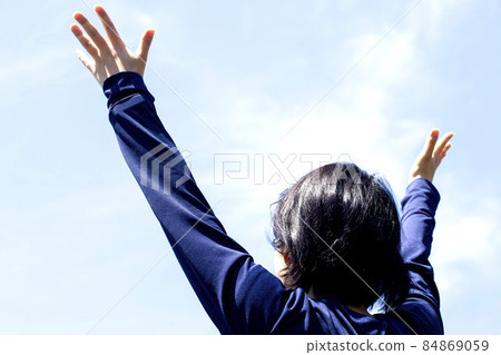 A young woman is looking up with her hands open under the sky A young woman is looking up with her hands open under the sky 84869059