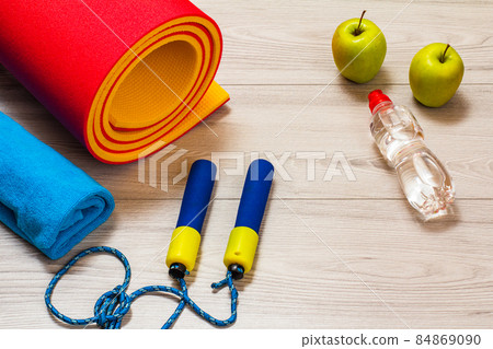 Yoga mat and different tools for fitness on floor in room. 84869090