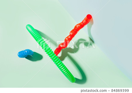 The curved pop tube stands leaning against the wall. Modern still life with antistress toy 84869399
