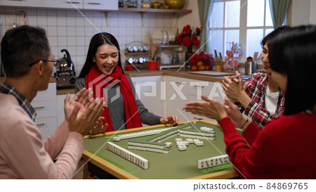 family members clapping hands for the winning daughter who claims a discarded tile and completes her hand while playing mahjong game at home on chinese lunar new year's eve family members clapping hands for the winning daughter who claims a discarded tile and completes her hand while playing mahjong game at home on chinese lunar new year's eve 84869765