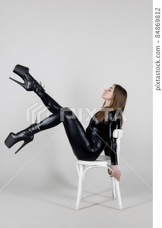 Sexy beautiful woman pole dancer posing in latex costume on background. 84869812