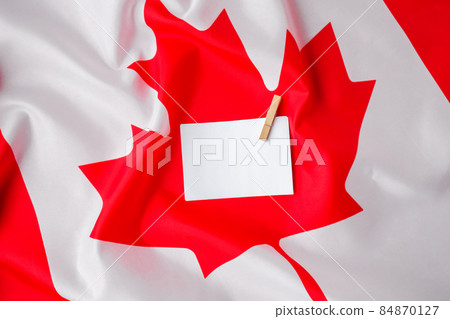 The National Flag of Canada. Canadian Flag or the Maple Leaf with empty paper note Copy space. Tourist traveler or patriotism. International relations concept. Independence day The National Flag of Canada. Canadian Flag or the Maple Leaf with empty paper note Copy space. Tourist traveler or patriotism. International relations concept. Independence day 84870127