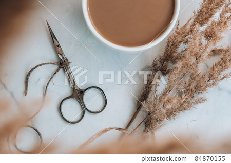 Manicure scissors with empty notebook and cup of coffee on table. Creative stylish workplace of manicurist. beauty treatment Manicure scissors with empty notebook and cup of coffee on table. Creative stylish workplace of manicurist. beauty treatment 84870155