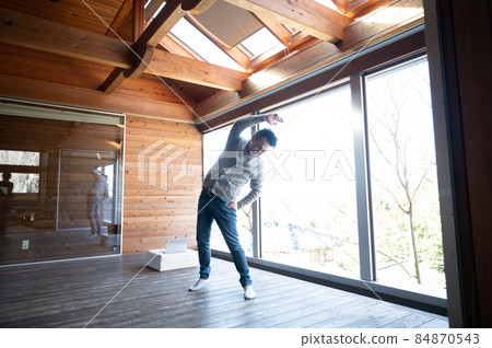 A Japanese man stretching on a stylish wooden deck against the sun during a break from work A Japanese man stretching on a stylish wooden deck against the sun during a break from work 84870543