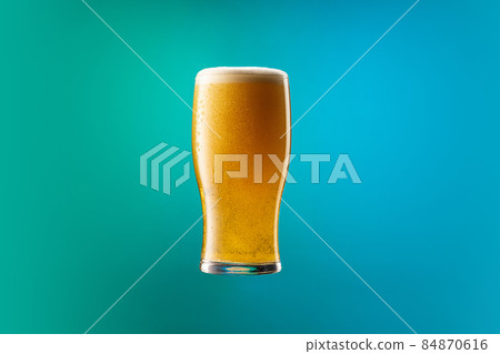 One full glass of frothy light beer isolated over gradient blue and green color background in neon. Concept of alcohol, drinks and festivals. One full glass of frothy light beer isolated over gradient blue and green color background in neon. Concept of alcohol, drinks and festivals. 84870616