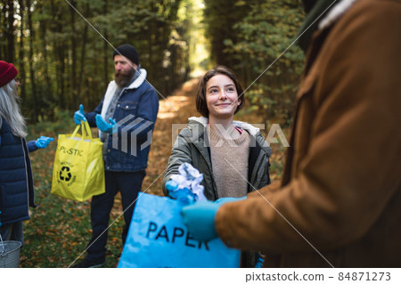 Diverse group of volunteers cleaning up forest from waste, community service concept 84871273