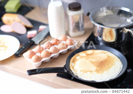 Thin pancake in a frying pan, cooking at home Thin pancake in a frying pan, cooking at home 84871442