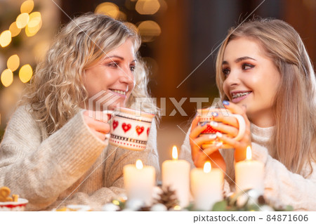 Mother with daughter drinking punch tea coffee or mulled wine at the holiday table during the Christmas holidays Mother with daughter drinking punch tea coffee or mulled wine at the holiday table during the Christmas holidays 84871606