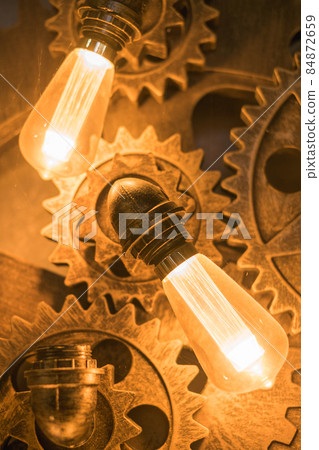 Steampunk architectural style design element of interior.Lamp bulbs fixed on iron industrial gear cogwheels sprocket lighting illuminated equipment Steampunk architectural style design element of interior.Lamp bulbs fixed on iron industrial gear cogwheels sprocket lighting illuminated equipment 84872659