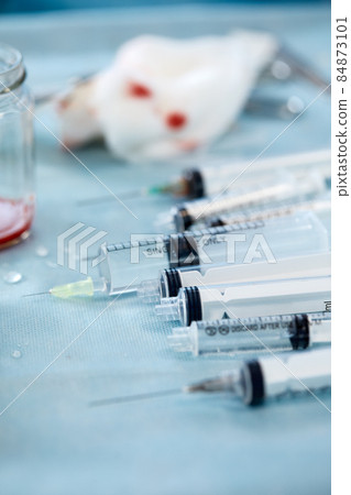 Many syringes on a blue sheet in operation room. Different sizes of syringes ready to be used 84873101