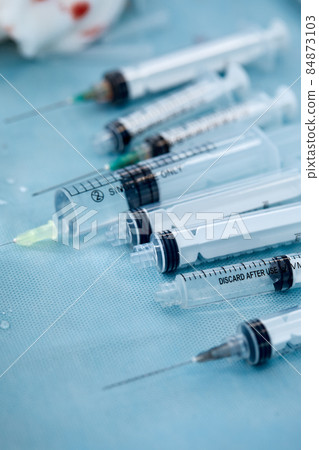 Many syringes on a blue sheet in operation room. Different sizes of syringes ready to be used 84873103