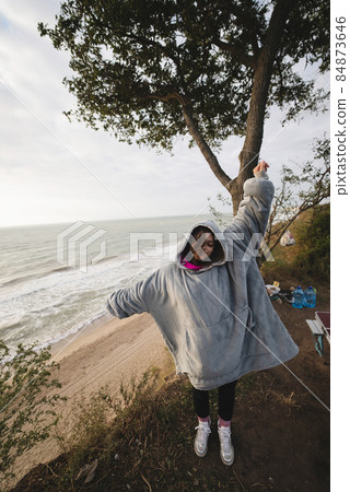 Young woman on cold autumn seashore posing at camera Young woman on cold autumn seashore posing at camera 84873646
