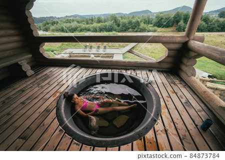 Woman relaxing in round outdoor bath. Organic skin care in hot bath Woman relaxing in round outdoor bath. Organic skin care in hot bath 84873784