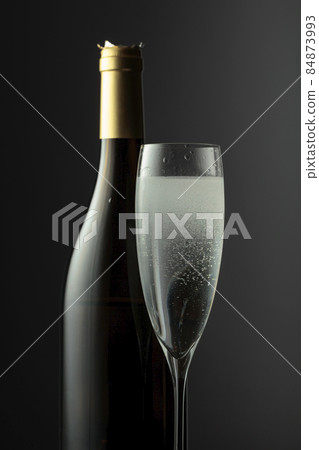 Bottle and glass of champagne on a black background. 84873993