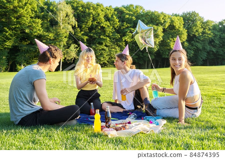 Teenage birthday party picnic on the grass in the park Teenage birthday party picnic on the grass in the park 84874395