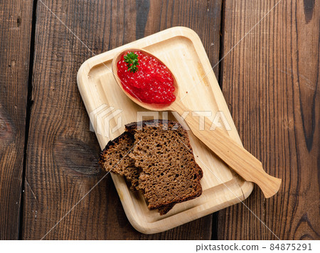 red caviar of pink salmon lies in a wooden spoon on a cutting board. Brown wooden table red caviar of pink salmon lies in a wooden spoon on a cutting board. Brown wooden table 84875291