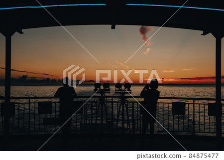 Silhouette of a person watching the sunrise from a ship Silhouette of a person watching the sunrise from a ship 84875477