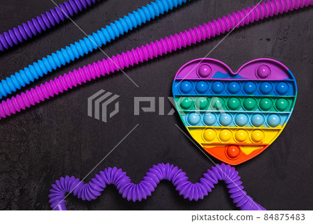 Pop it heart and tube toys on black concrete Pop it heart and tube toys on black concrete 84875483