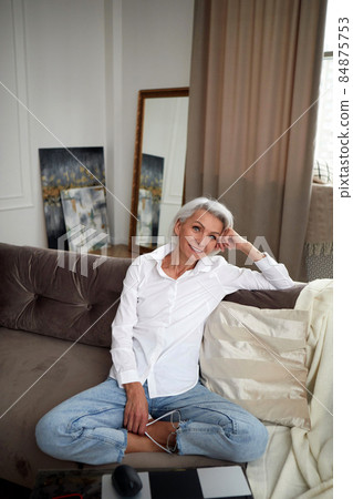 Delighted mature woman in stylish clothes on sofa Delighted mature woman in stylish clothes on sofa 84875753