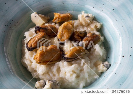 Seafood risotto in a blue plate on a gray background, top view. Risotto with mussels and dor blue cheese. Haute cuisine in restonan. Delicious and healthy 84876086