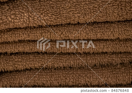A stack of soft bath accessories. Texture of brown terry towel close-up. 84876848