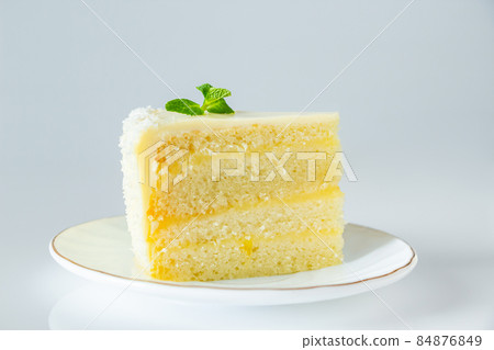 Lemon cake with coconut flakes. A piece of delicate vanilla dessert with cream. 84876849