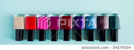 Group of bright colored nail polishes on a blue background. Set of decorative cosmetics for body care. Banner format Group of bright colored nail polishes on a blue background. Set of decorative cosmetics for body care. Banner format 84876884