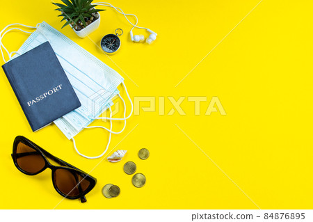 Safe travel during the coronavirus pandemic. New normal. Medical mask and sunglasses on a yellow background. Flatlay, copy space. Safe travel during the coronavirus pandemic. New normal. Medical mask and sunglasses on a yellow background. Flatlay, copy space. 84876895
