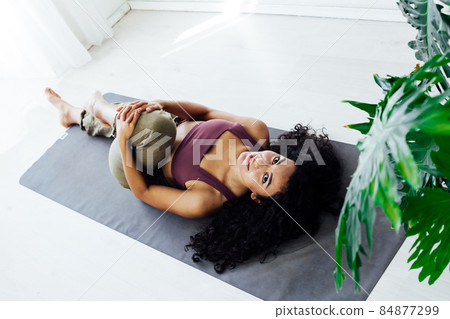 woman brunette doing exercises yoga asana gymnastics in white hall woman brunette doing exercises yoga asana gymnastics in white hall 84877299