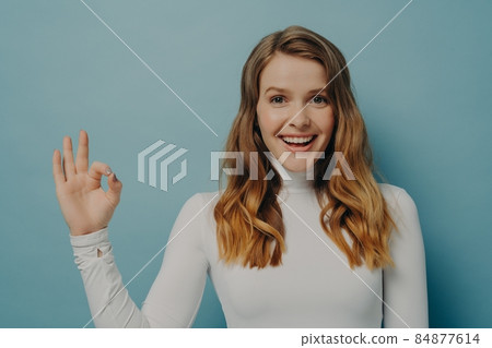 Beautiful excited joyful young lady with dyed light-brown hair gesturing ok symbol with fingers Beautiful excited joyful young lady with dyed light-brown hair gesturing ok symbol with fingers 84877614