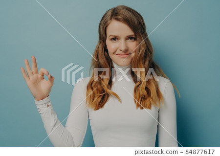 Cheerful young european woman showing okay gesture isolated over pastel blue studio wall Cheerful young european woman showing okay gesture isolated over pastel blue studio wall 84877617