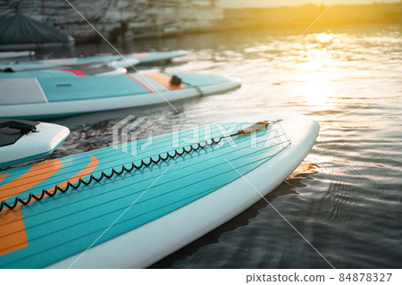 Close up stand up paddle board SUP on lake with water lilies, paddling in summer time on dark blue water at sunset 84878327