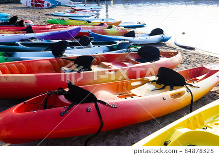 Colorful plactic kayaks or canoe on the beach sand for tourist rent. Surfing boards on stand during summer season 84878328