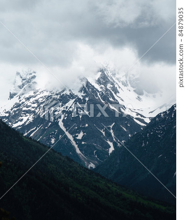 Snow on top of the mountain, clouds around 84879035