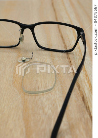 The lens on the table and the broken glasses with the nose pad removed 84879667