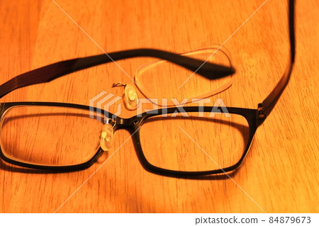 The lens on the table and the broken glasses with the nose pad removed 84879673