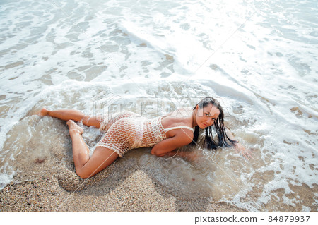beautiful tanned woman in a summer dress on the beach bathing in the sea beautiful tanned woman in a summer dress on the beach bathing in the sea 84879937