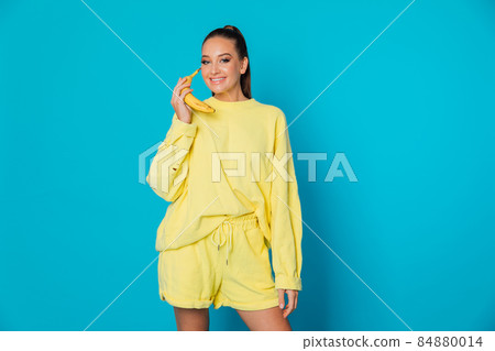 woman in yellow clothes with banana fruit on a blue background 84880014