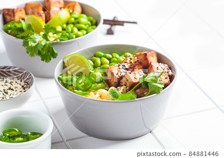 Vegan noodles ramen soup with marinated tofu, edamame beans and hot peppers in gray bowls. 84881446
