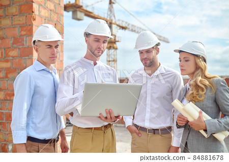 Woman and men looking at laptop at construction 84881678