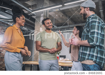 Interracial young happy colleagues communicating in office Interracial young happy colleagues communicating in office 84881691