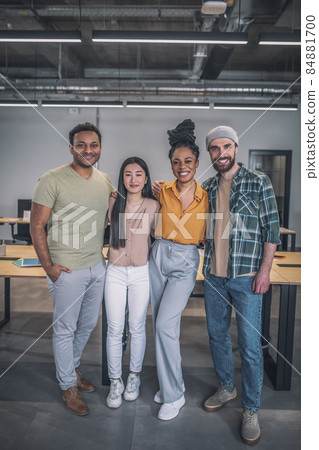 Four interracial young people standing hugging at office Four interracial young people standing hugging at office 84881700