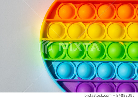 Close up round multicolored pop it toy and shadow on a white 84882395