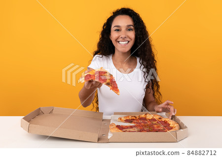 Happy Latin Lady Holding Pizza Offering Slice To Camera Happy Latin Lady Holding Pizza Offering Slice To Camera 84882712