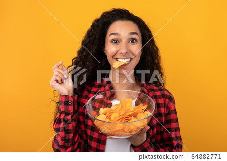 Excited Latin Lady Eating Delicious Potato Crisps Excited Latin Lady Eating Delicious Potato Crisps 84882771