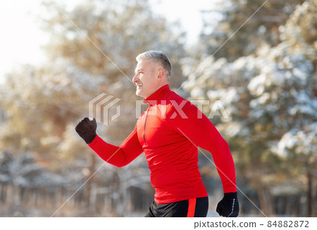 Athletic senior man in sportswear running at winter park, side view. Seasonal sports and tempering concept Athletic senior man in sportswear running at winter park, side view. Seasonal sports and tempering concept 84882872