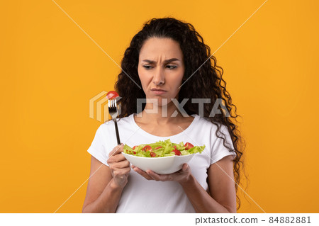 Portrait of Sad Latin Lady Holding Plate With Vegetable Salad 84882881