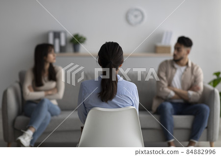 Female psychologist giving therapy session to quarreling middle eastern couple, helping them with conflict, back view Female psychologist giving therapy session to quarreling middle eastern couple, helping them with conflict, back view 84882996