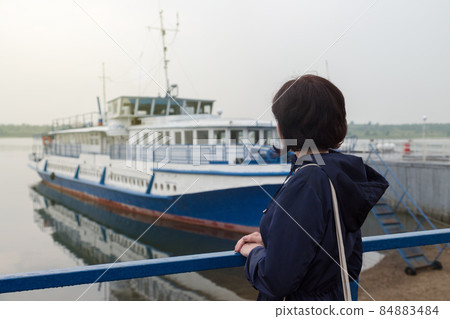 A brunette in a blue jacket awaits the arrival of the ship A brunette in a blue jacket awaits the arrival of the ship 84883484